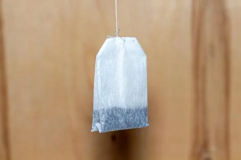 Single tea bag hanging on a string against a wooden background for morning Фото