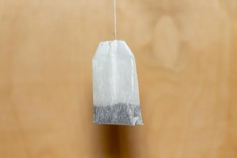 Single tea bag hanging on a string against a wooden background for brewing 库存照片