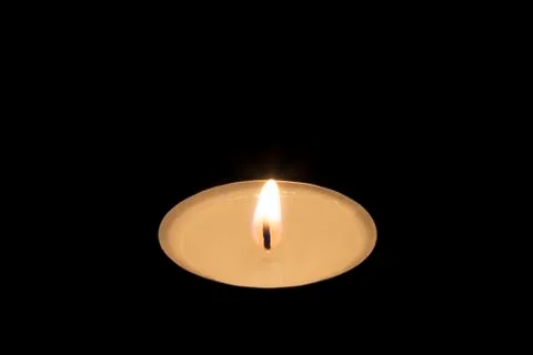 Single tea candle on black Stock Photos