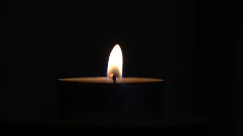 Single tea light candle burning with a bright steady flame against a pure black Stock Footage 347446240