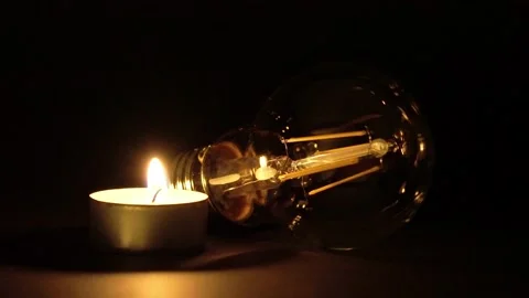 A single tea-light candle lit next to an LED bulb. 스톡 동영상 169758900