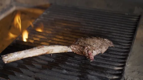Single tomahawk rib steak on hot black grill with flames underneath. Vídeos de archivo 117443310
