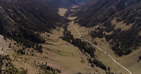 Single track path leads up valley into distant mountains drone aerial 4k Stock Footage 125757192