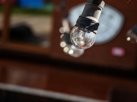 A single transparent light bulb in a black plinth on a blurred background Stock Photos