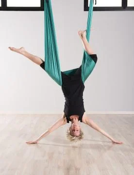 Single upside down woman doing aerial yoga Stock Photos