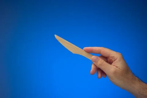 Single use disposable and biodegradable wooden knife held in hand by Caucasia Stock Photos