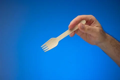 Single use disposable and biodegradable wooden spoon held in hand by Caucasia Stock Photos