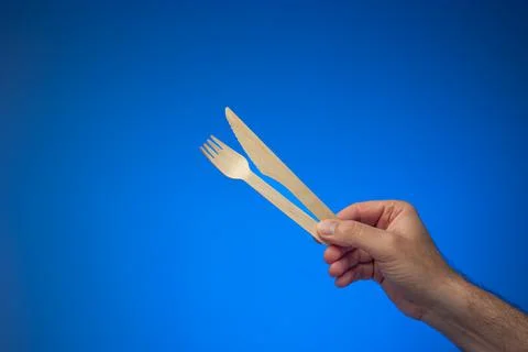 Single use disposable and biodegradable wooden knife and fork held in hand by Photos