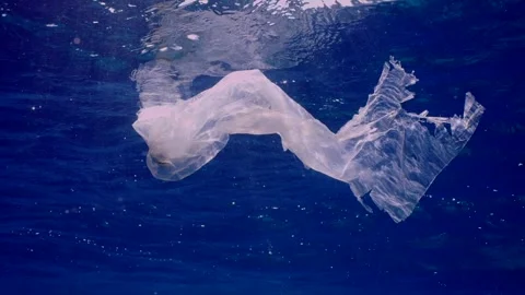 Single use plastic discarded bag floating in blue sea, Slow motion Stock Footage 246358913