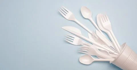 Single-use plastic products: plastic cutlery, cups on bright blue background Foto stock