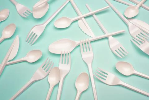 Single-use plastic products: plastic cutlery, cups on bright blue background Stock Photos