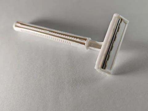 Single use white plastic disposable razor on textured gray background, close Foto stock
