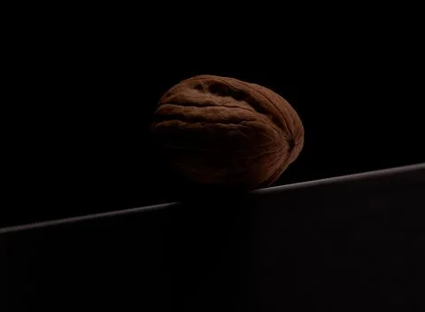 A single walnut rests on a dark, reflective surface Foto stock