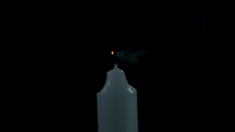 A single white candle flame being blown out in darkness Video stock 334873565