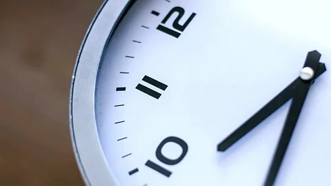 Single white clock hanging on wall time lapse cinematic concept of film Stock Footage 336445060