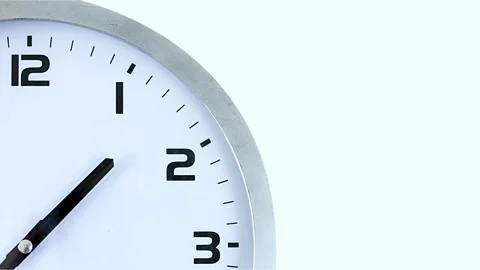 Single white clock hanging on wall time lapse cinematic concept of film Stock Footage 336445066