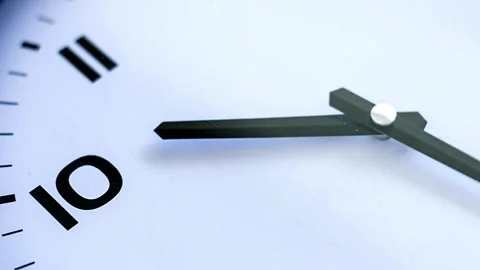Single white clock hanging on wall time lapse cinematic concept of film Stock Footage 336445074