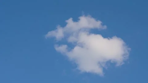 Single white cloud drifting across clear blue sky. Minimal nature scene with Stock Footage 333140706