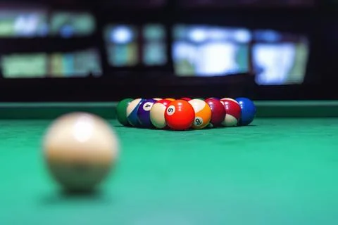 A single, white cue ball rests on a vibrant green pool table Stock Photos