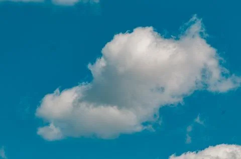 Single White Cumulus Cloud in a Bright Blue Sky Stock Photos