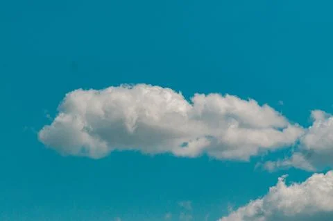 Single White Cumulus Cloud in a Clear Bright Blue Sky Stock Photos