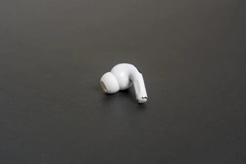 Single white earbud rests on dark surface Stock Photos