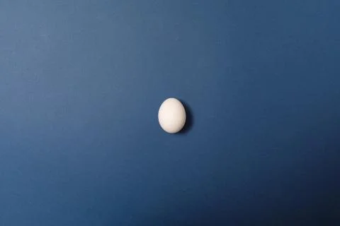 Single white egg on blue background. Holiday concept. Happy Easter Foto stock