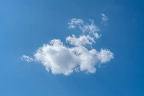 Single white fluffy cloud floating in the clear blue sky on a bright sunny da Фото