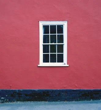 Single white framed window set against a red painted house brickwall Stock Photos