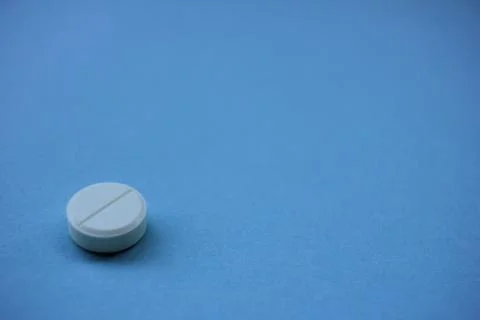 Single white pill on a blue background with copy space Stock Photos