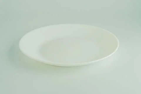 A single, white, reflective plate on a flat surface Photos