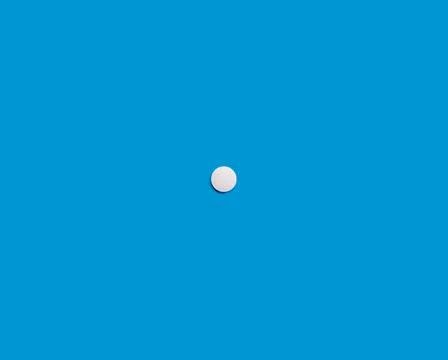 A single white tablet on a blue background. Medical pharmaceutical concept. T Stock Photos