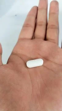 Single white tablet on open palm Stock Photos