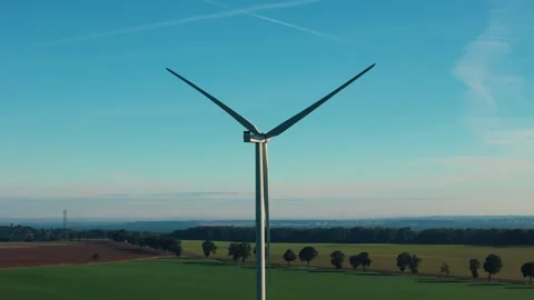 Single wind turbine with blades turning over agricultural land Video stock 336900635