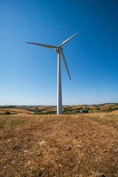 A single wind turbine generates clean energy on a bright clear sky day Фото