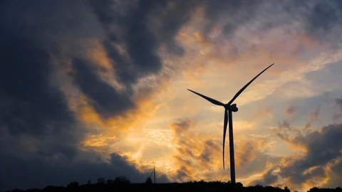 A single wind turbine revolves around energy production with a dark yellow sky Stock Footage 115475677