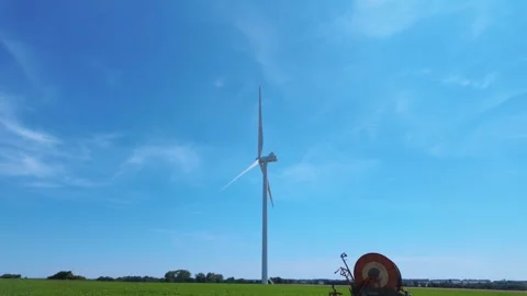 Single wind turbine rotating over green crop field, wide shot, Normandy Stock Footage 347791372