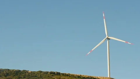 Single wind turbine spins around generating energy in the blue sky. Stock Footage 128057451