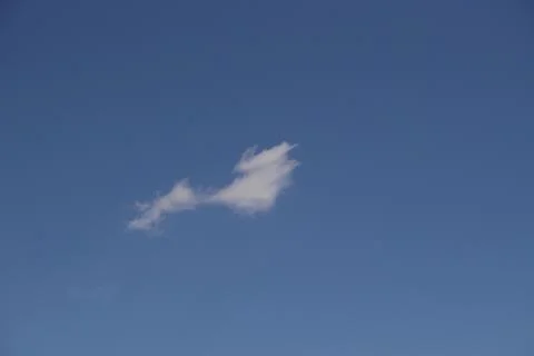 Single Wispy White Cloud Drifting Across a Vast Clear Vibrant Blue Sky Conc.. 写真素材