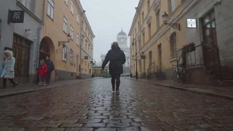 Single woman walking down an empty, wet cobbled street in Helsinki, Finland Stock Footage 146291227