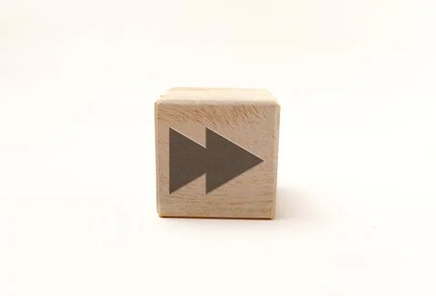 Single wooden block cube featuring a gray fast-forward double-arrow icon on.. Stock Photos