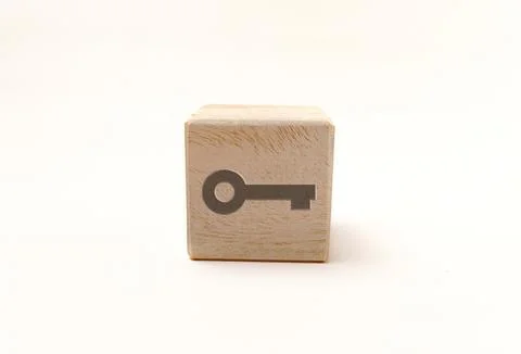 Single wooden block cube featuring a gray door key security icon on natural.. Stock Photos