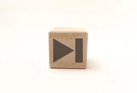 Single wooden block cube featuring a gray skip to next media icon on natura.. Stock Photos