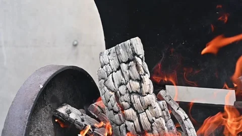 Single wooden log burning with bright orange flames in an outdoor grill Stock Footage 340273582