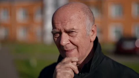 Single wrinkled elderly man is standing on street in sunny autumn day, portrait Stock Footage 166097704