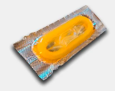 SINGLE YELLOW CONDOM IN FOIL WRAPPER ON WHITE BACKGROUND Stock Photos