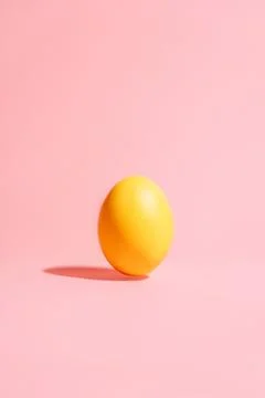 Single yellow Easter egg on pink background, minimal vertical copy space 스톡 사진