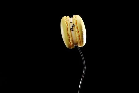 Single yellow Macaron or macaroon cake on a Fork, french dessert isolated on Stock Photos
