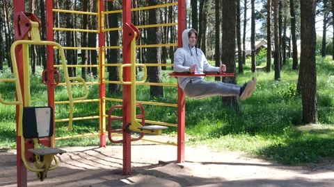 Single young man doing exercises at street gym apparatus in park, street workout Vídeos de archivo 136236064