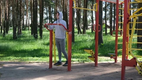 Single young man doing exercises at street gym apparatus in park, street workout Stock Footage 152222650